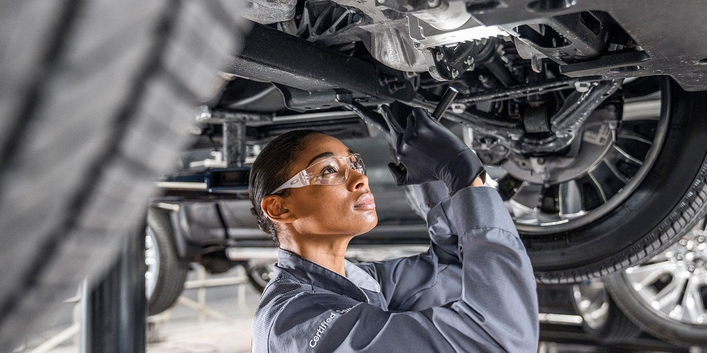 Technician inspecting the underside of a GMC vehicle during a pre owned inspection in Graham, TX