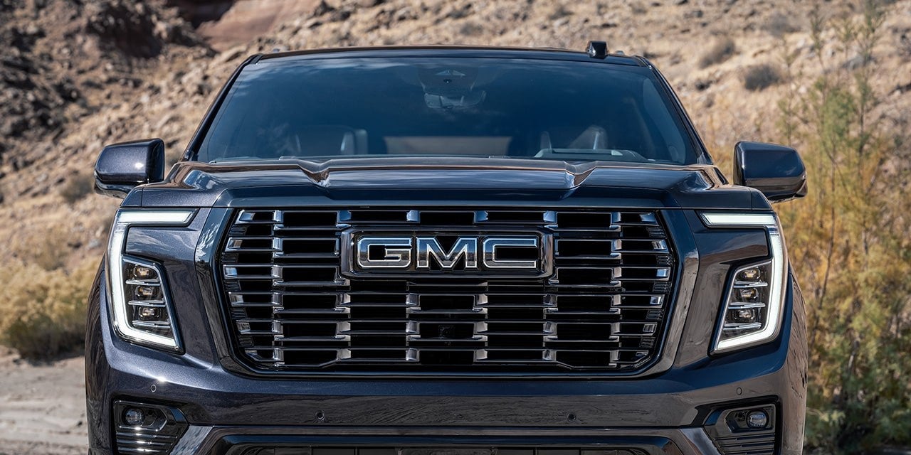 Front grille of a dark GMC Yukon parked in a desert landscape