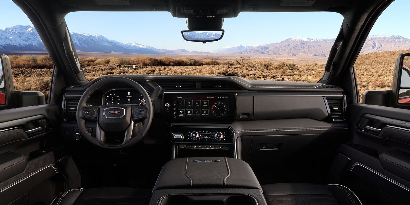 Dashboard and front seats inside a GMC Sierra HD with a desert view through the windshield