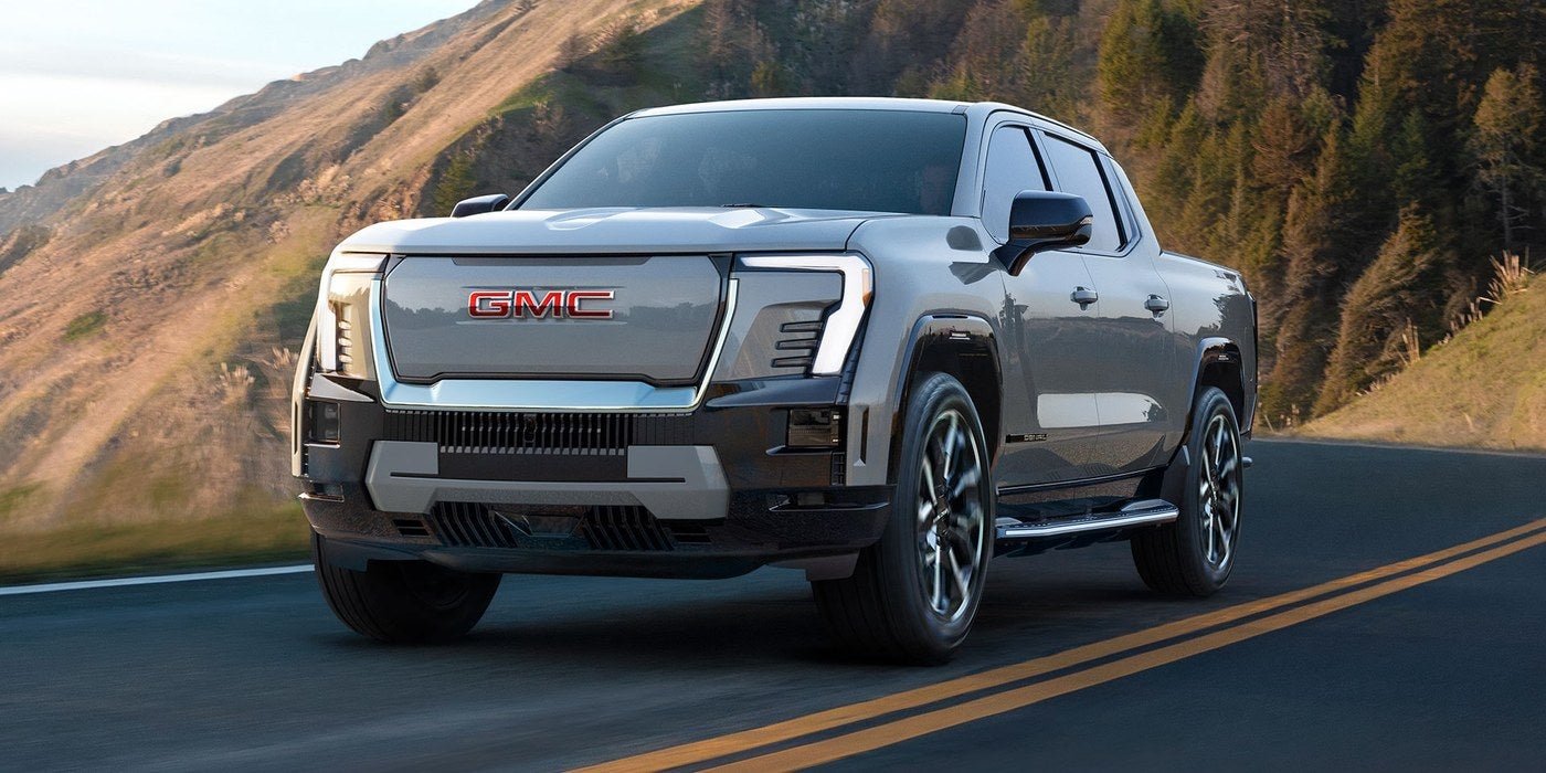 GMC Sierra EV pickup driving along a hillside road