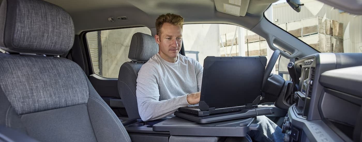 A person using a laptop in a 2026 Ford F-350.