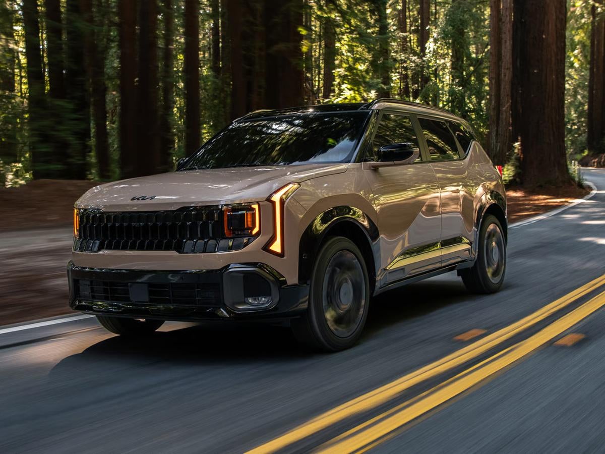 2027 Kia Seltos X-Line driving on a scenic forest road with bold exterior styling and available all-wheel drive