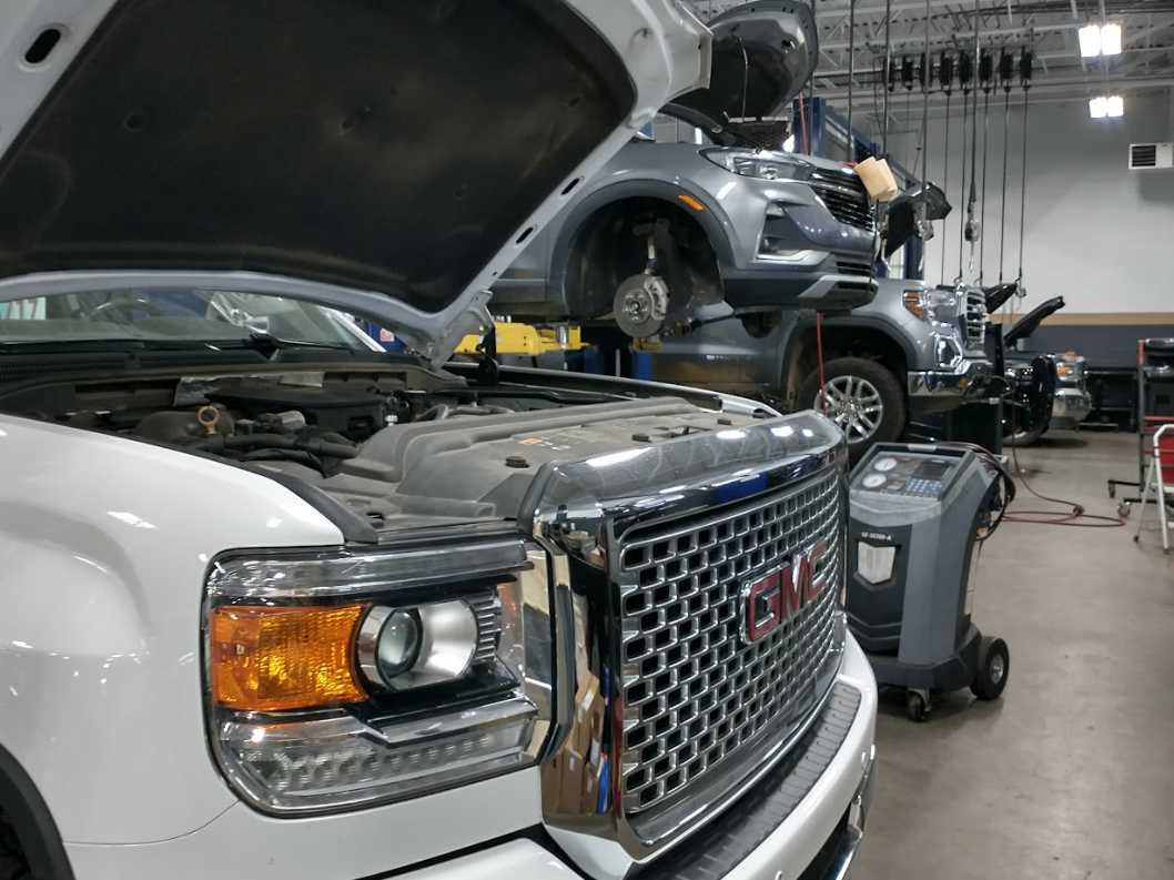 GMC and Buick SUVs undergoing service with hoods open and tires off at Crain Buick GMC’s certified service center in Conway