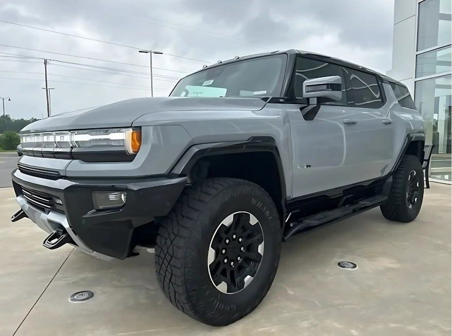 Front and side view of a GMC Hummer EV SUV in gray, equipped with CrabWalk mode, parked outside Crain Buick GMC in Conway
