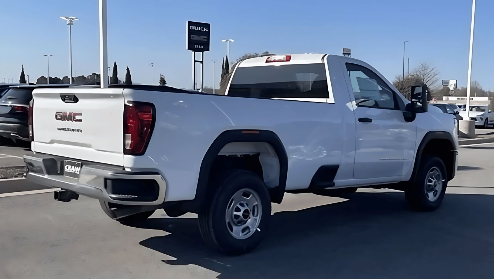Rear and side view of a white 2025 GMC Sierra 1500 regular cab pickup parked at Crain Buick GMC in Conway, Arkansas