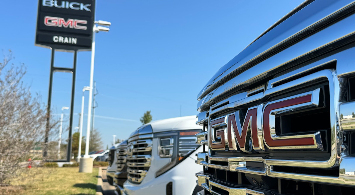 Close-up of GMC truck grille with Crain Buick GMC dealership sign in the background in Conway, Arkansas