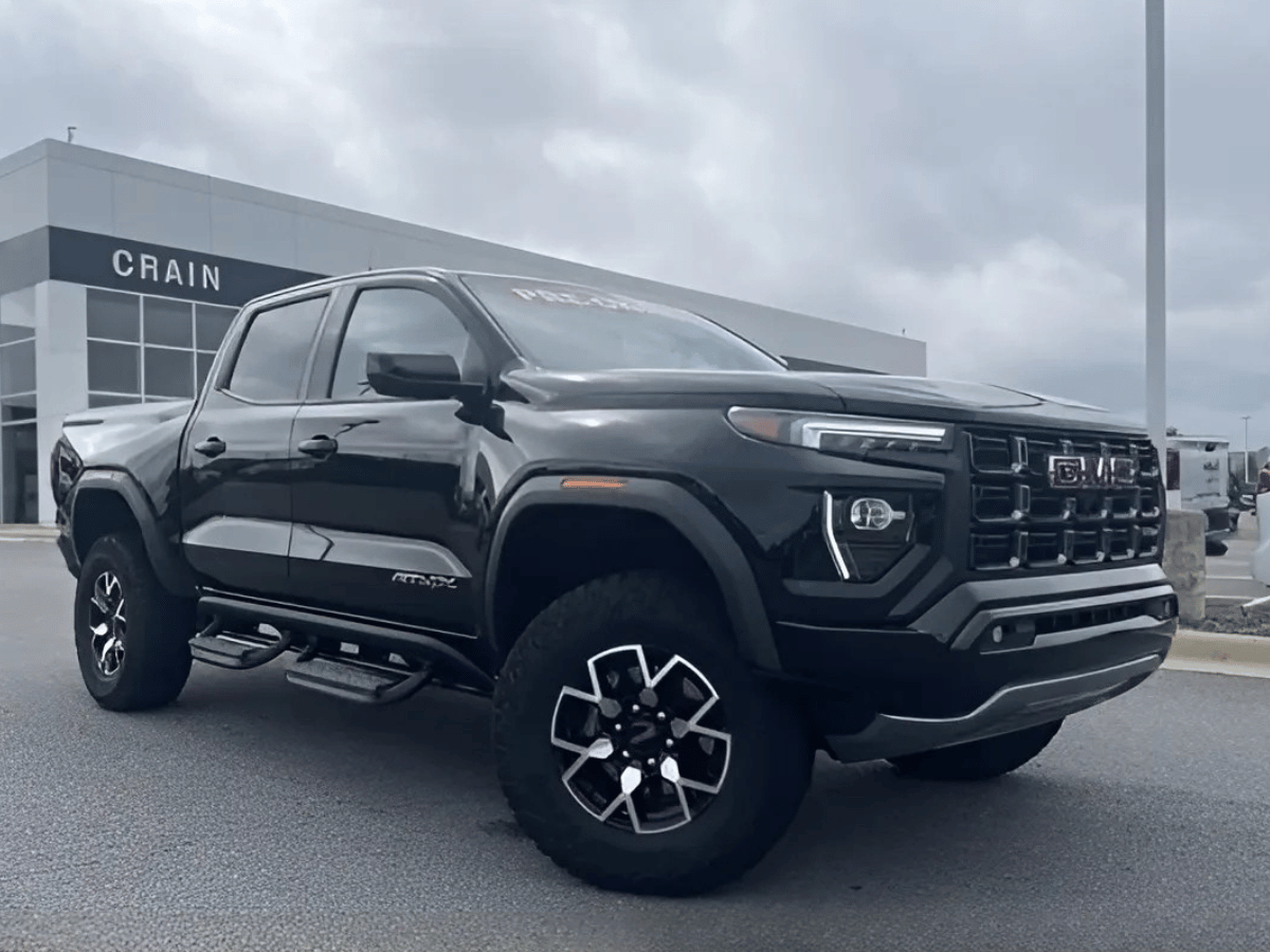 Black used GMC Canyon truck parked in front of Crain Buick GMC dealership in Conway, AR
