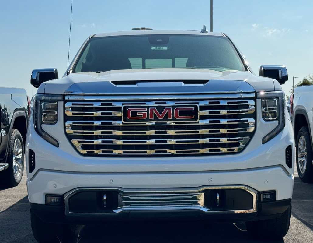 Front view of a white GMC Sierra with chrome grille, parked at Crain Buick GMC in Conway, Arkansas