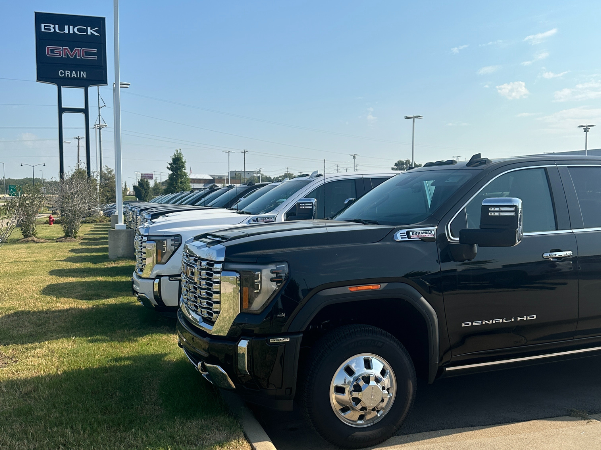 Row of new 2024 GMC trucks, including a black Denali HD, on display at Crain Buick GMC in Conway, Arkansas