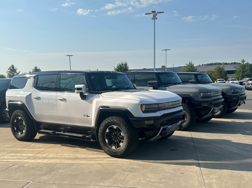Row of GMC Hummer EV SUVs in white and gray parked at Crain Buick GMC in Conway, Arkansas under clear fall skies