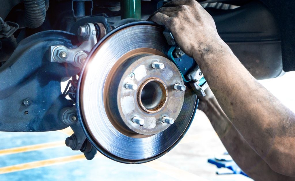 Ford technician inspecting brake system during vehicle service in Shallotte, NC