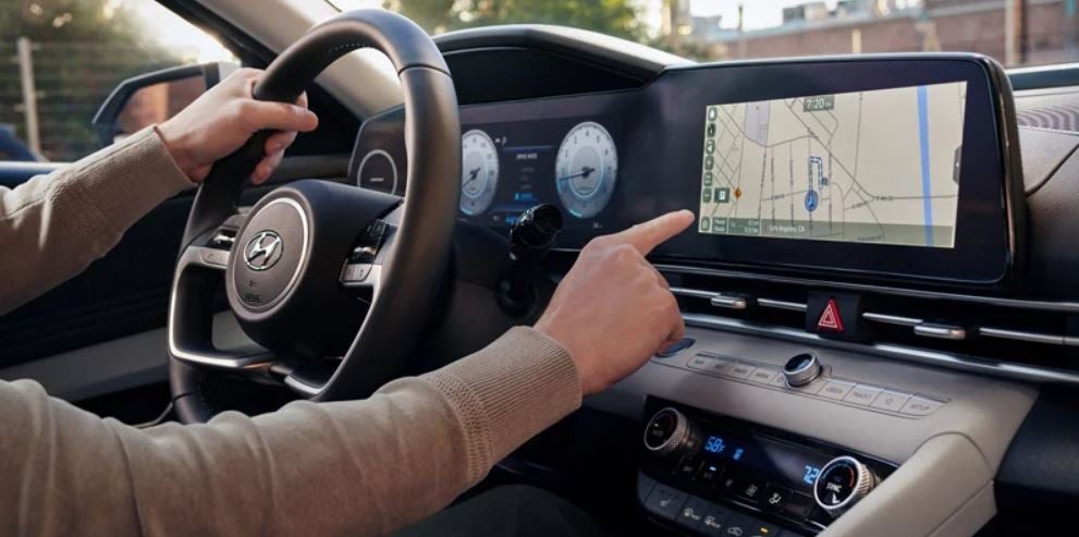 Driver using the touchscreen navigation system inside the 2023 Hyundai Elantra
