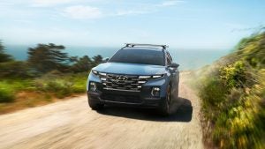 Front view of a light blue 2022 Hyundai Santa Cruz being driven on a dirt road. | Hyundai dealer in North Little Rock, AR.
