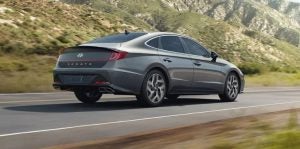 Rear view of a gray 2021 Hyundai Sonata being driven on the highway with mountains in the background. | Hyundai dealer in North Little Rock, AR.