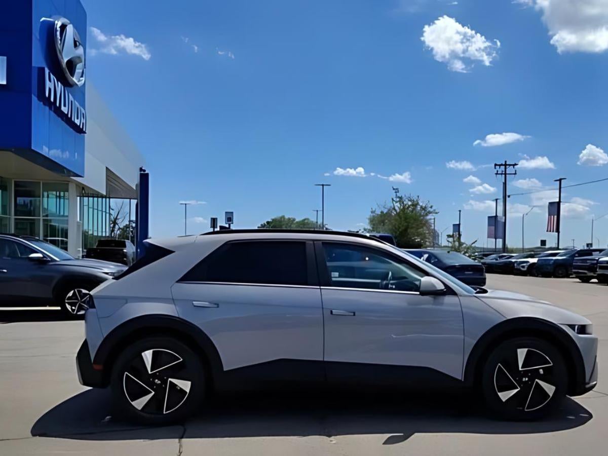Silver Hyundai IONIQ 5 electric SUV parked outside Crain Hyundai of Fort Smith dealership under a sunny sky