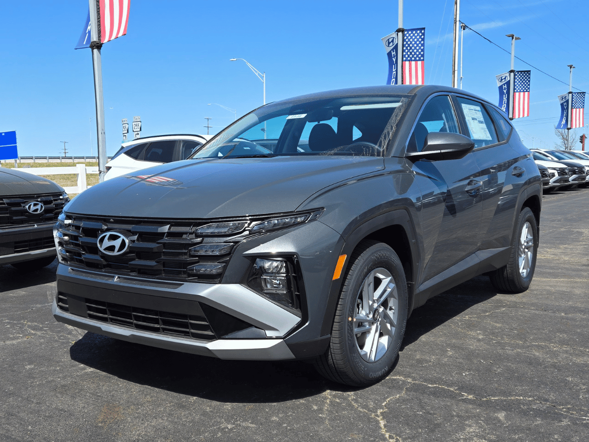 2025 Hyundai Tucson Hybrid SUV on display at Crain Hyundai of Fort Smith dealership with flags and inventory in background