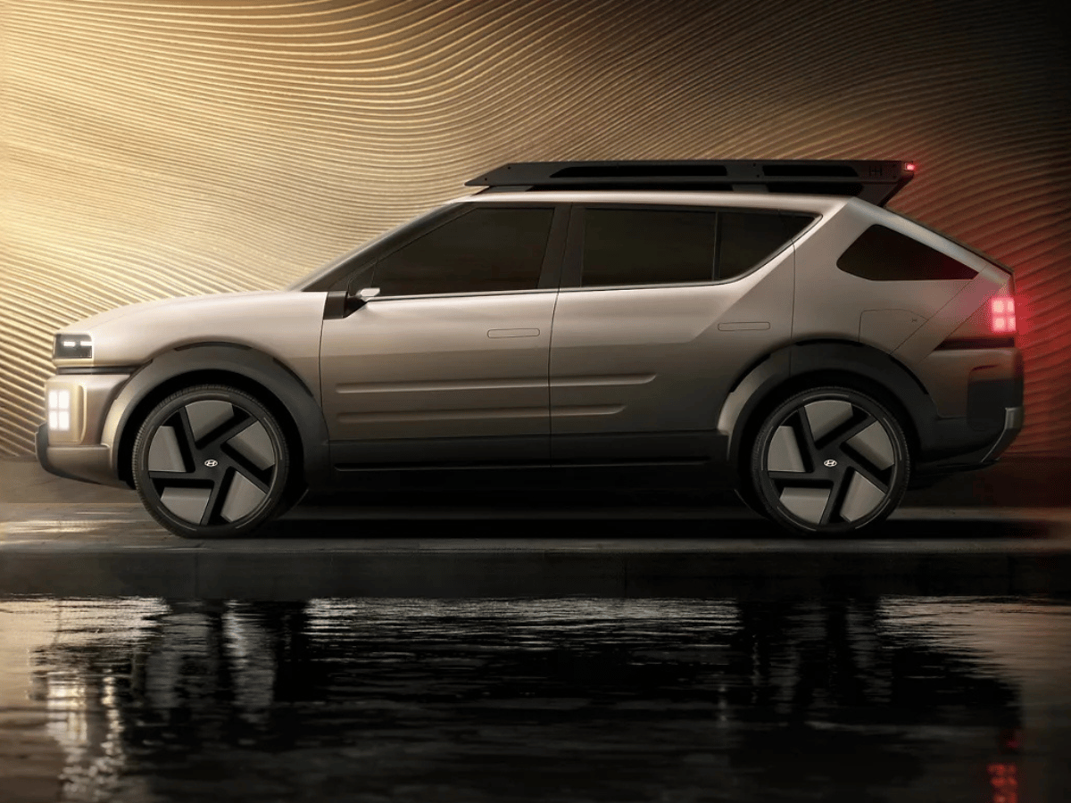 Side profile of the futuristic Hyundai Initium hydrogen SUV, parked near water with a glowing background.