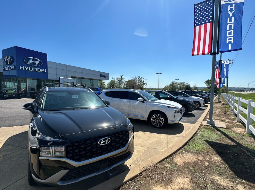 Lineup of Hyundai SUVs at Crain Hyundai dealership under blue sky and American flags