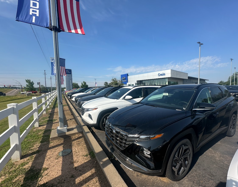 A row of new Hyundai SUVs lined up at Crain Hyundai of Fort Smith, ready for lease, with dealership signage and American flags in view.