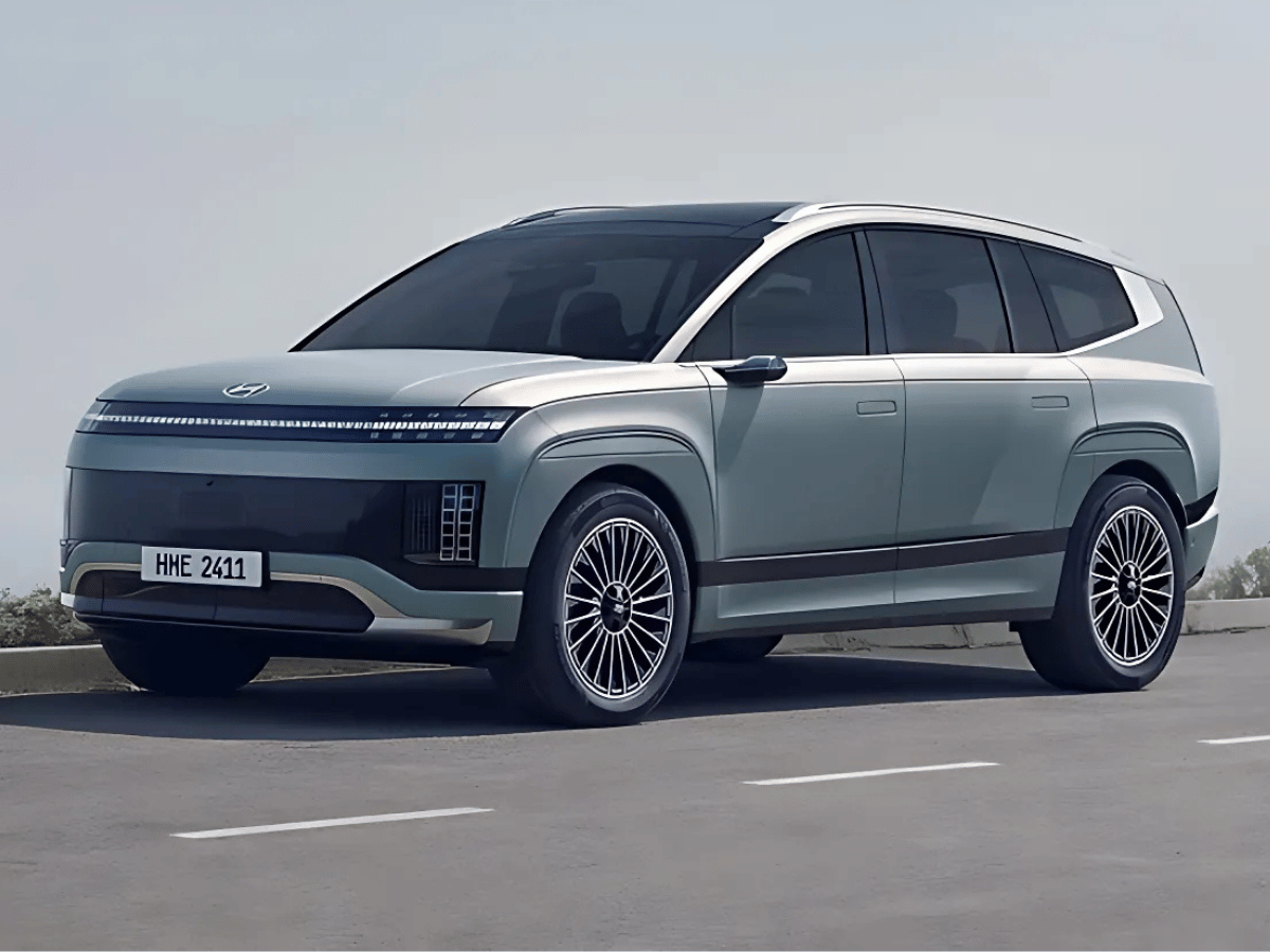 A futuristic Hyundai Ioniq 9 electric SUV in matte blue parked on the road under clear skies, showcasing sleek design and aerodynamic curves.