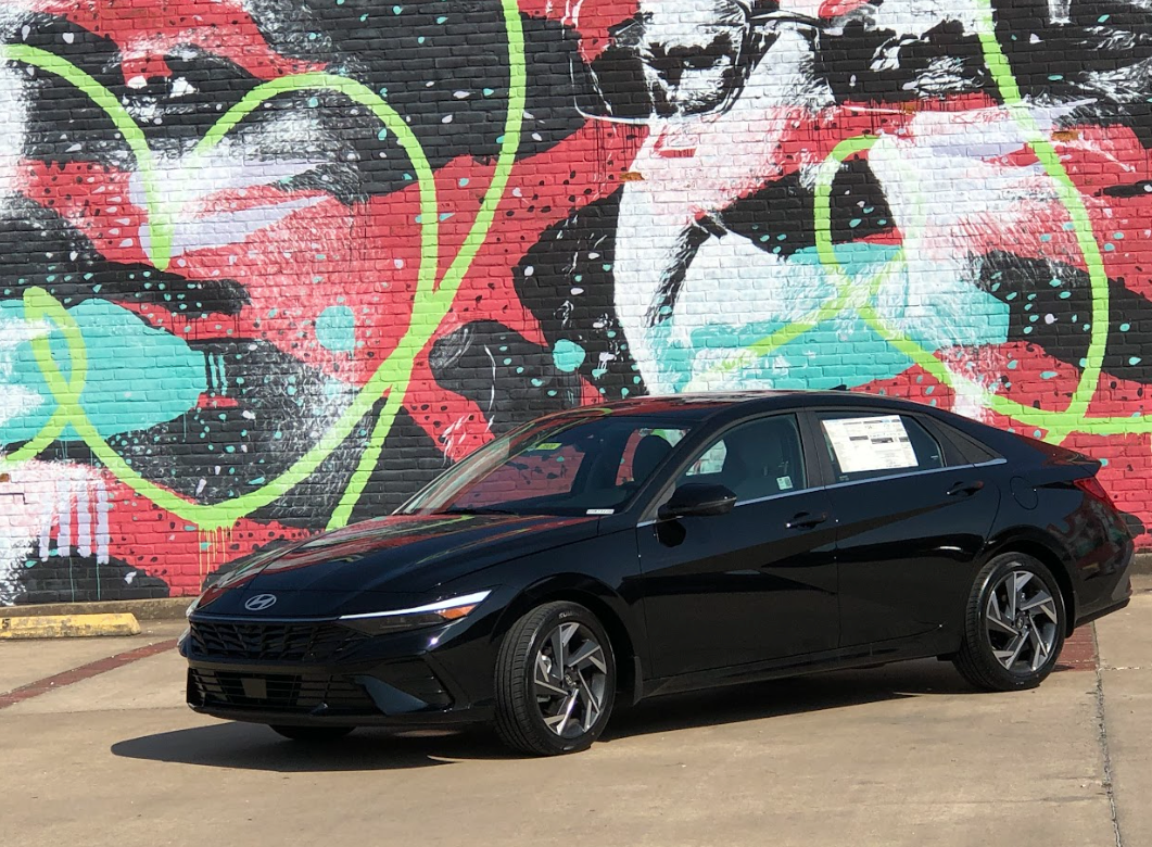 A sleek black Hyundai Elantra parked in front of a colorful street mural in Fort Smith, Arkansas.