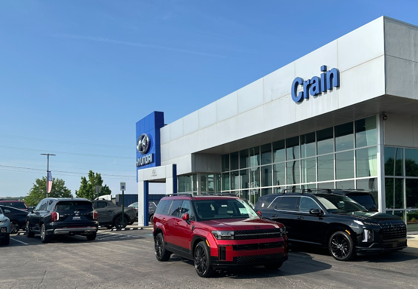 Crain Hyundai of Fort Smith dealership lot with Hyundai SUVs parked out front, including a red Santa Fe, on a clear blue-sky day.