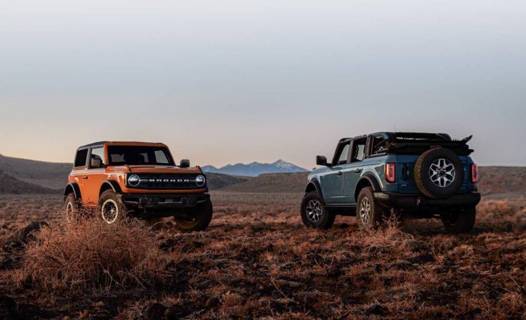 A orange and a blue 2021 Ford Bronco parked in an open field. Ford dealer in Jacksonville, AR.