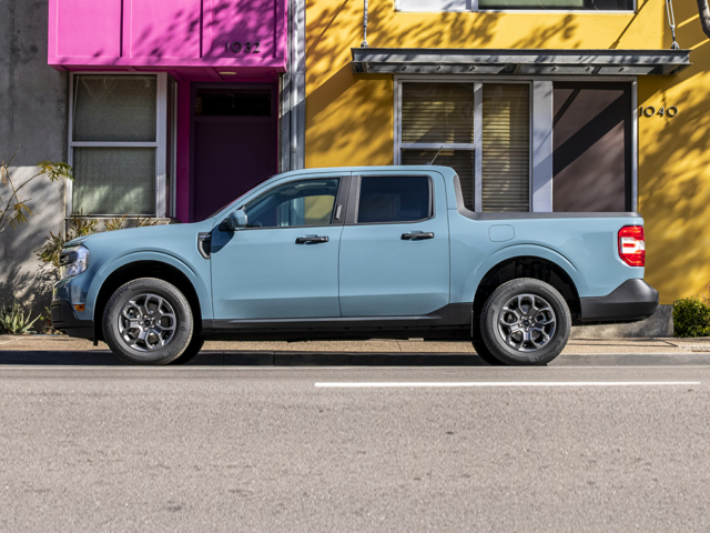 Profile view of a light blue 2024 Ford Maverick parked in front of a purple and yellow building. | Ford dealer in Jacksonville, AR | Crain Ford of Jacksonville
