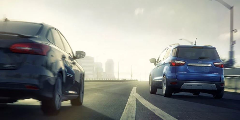 A blue 2021 Ford EcoSport being driven onto the highway with a car in the lane beside it. | Ford dealer in Little Rock, AR.