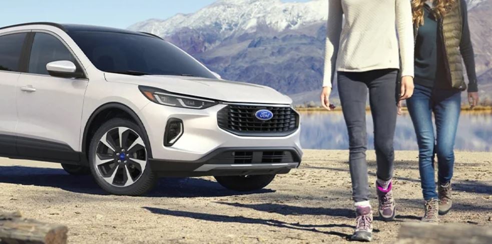 Two women walking in front of a white 2023 Ford Escape. | Ford dealer in Little Rock, AR.