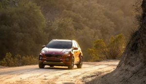 A red 2022 Kia Sportage parked on a dirt road with trees in the background. | Kia dealer in Sherwood, AR.