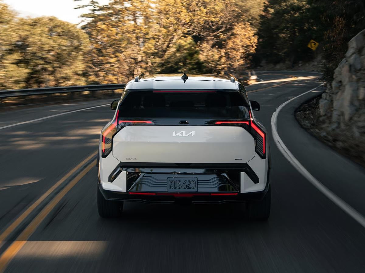 White 2027 Kia EV3 driving on a winding road