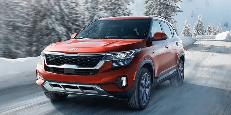 A red 2022 Kia Seltos driven on the road in the winter. | Kia dealer in Conway, AR.