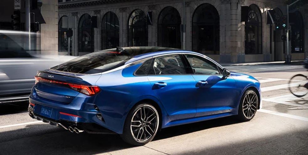A royal blue 2022 Kia K5 stopped at a stoplight. | Kia dealer in Conway, AR.