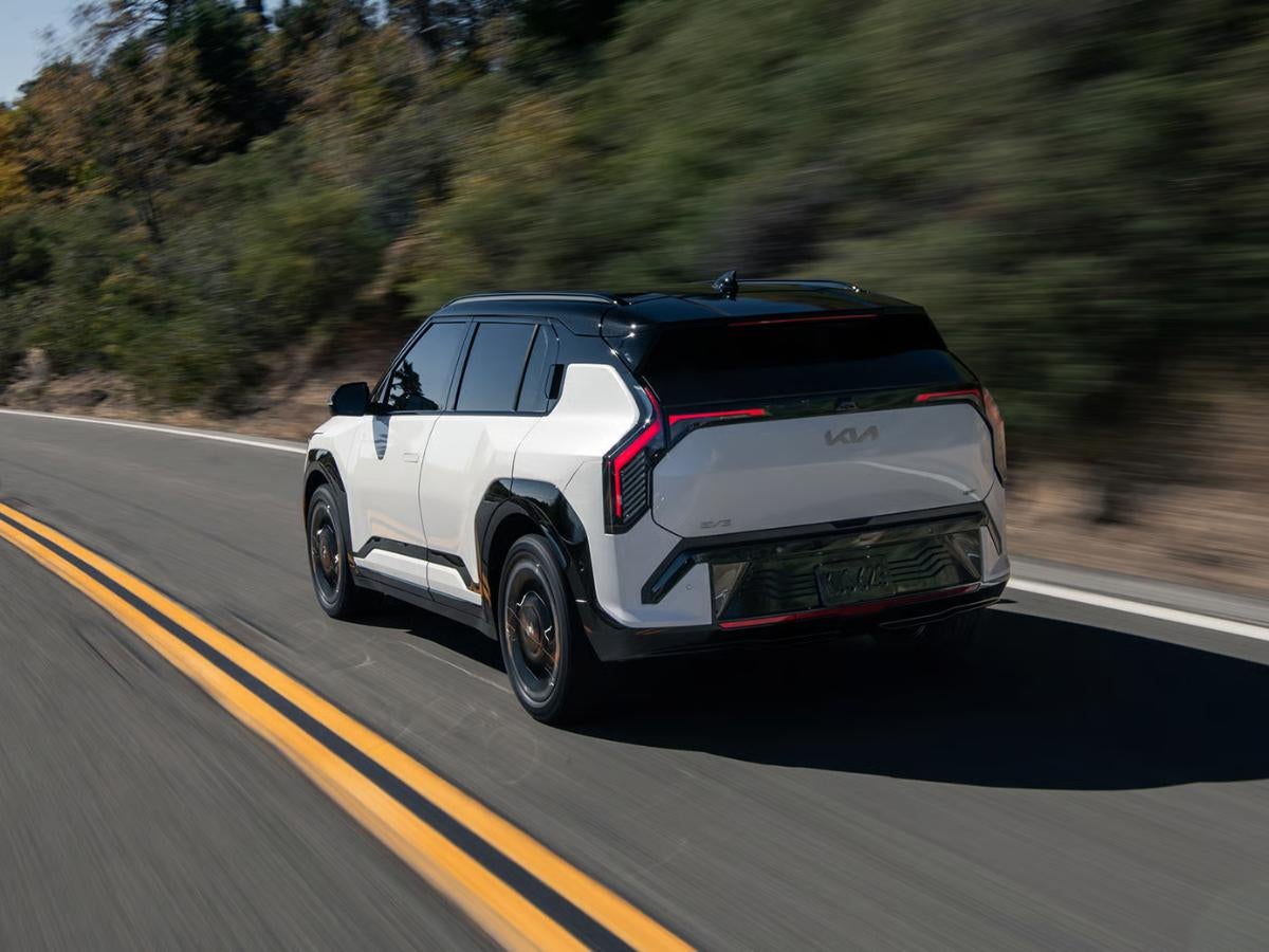 2027 Kia EV3 electric SUV driving on a scenic highway with advanced technology and modern design