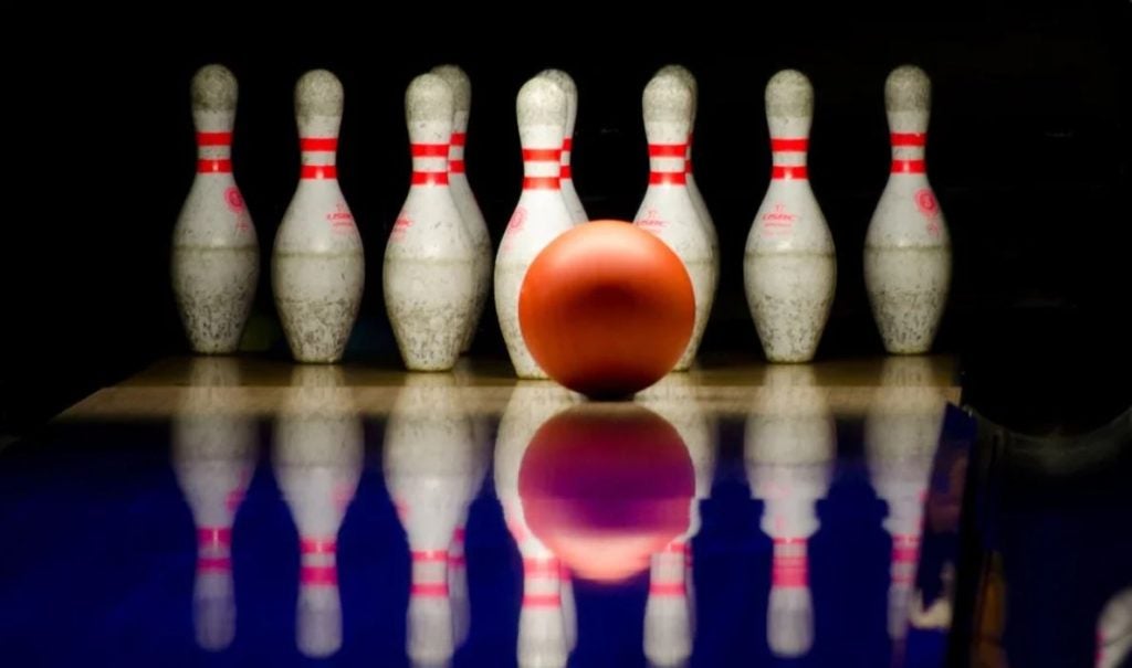An orange bowling ball in front of pins. | Bowling around Conway, AR.