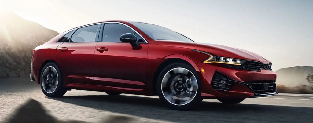 A red 2022 Kia K5 being driven on the road. | Kia dealer in Conway, AR.