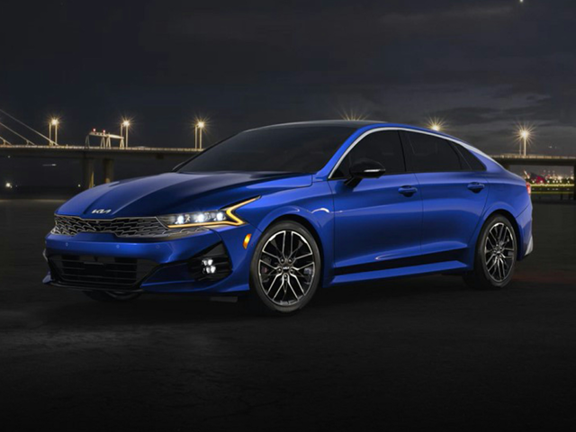 A parked, blue 2023 Kia K5 with the headlights on. | Kia dealer in Conway, AR | Crain Kia of Conway