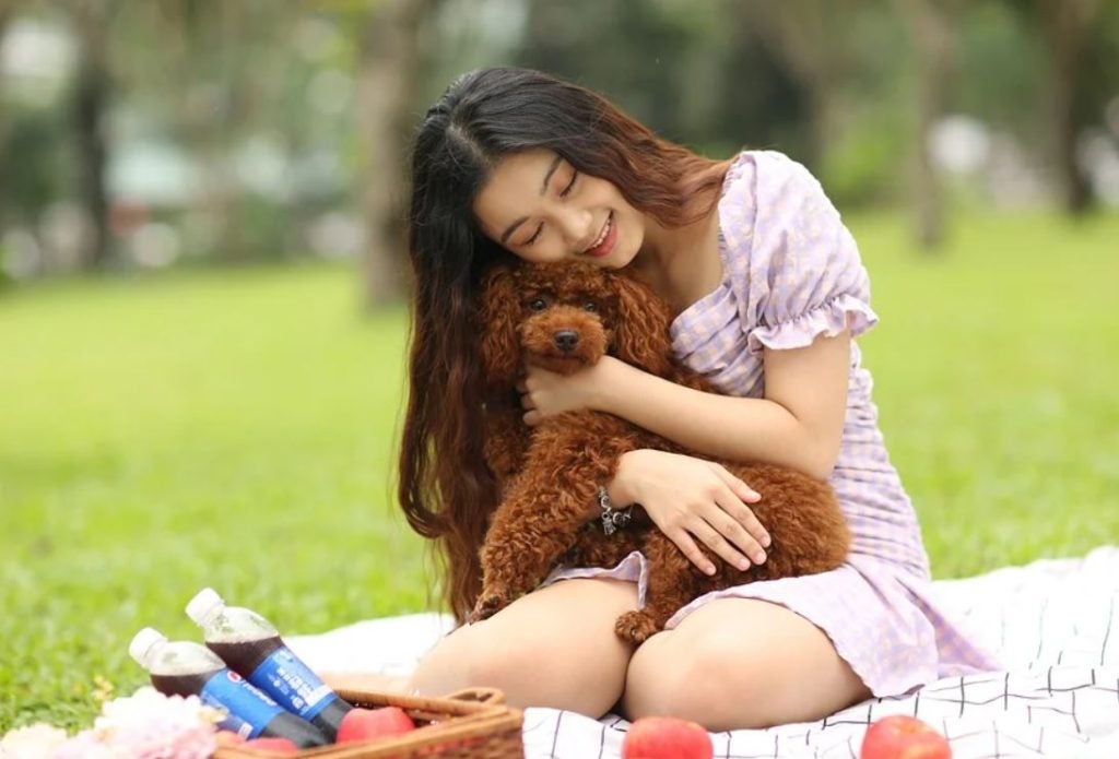 A girl and her dog sitting on a blanket with drinks and fruit. | Picnics around Bentonville, AR.