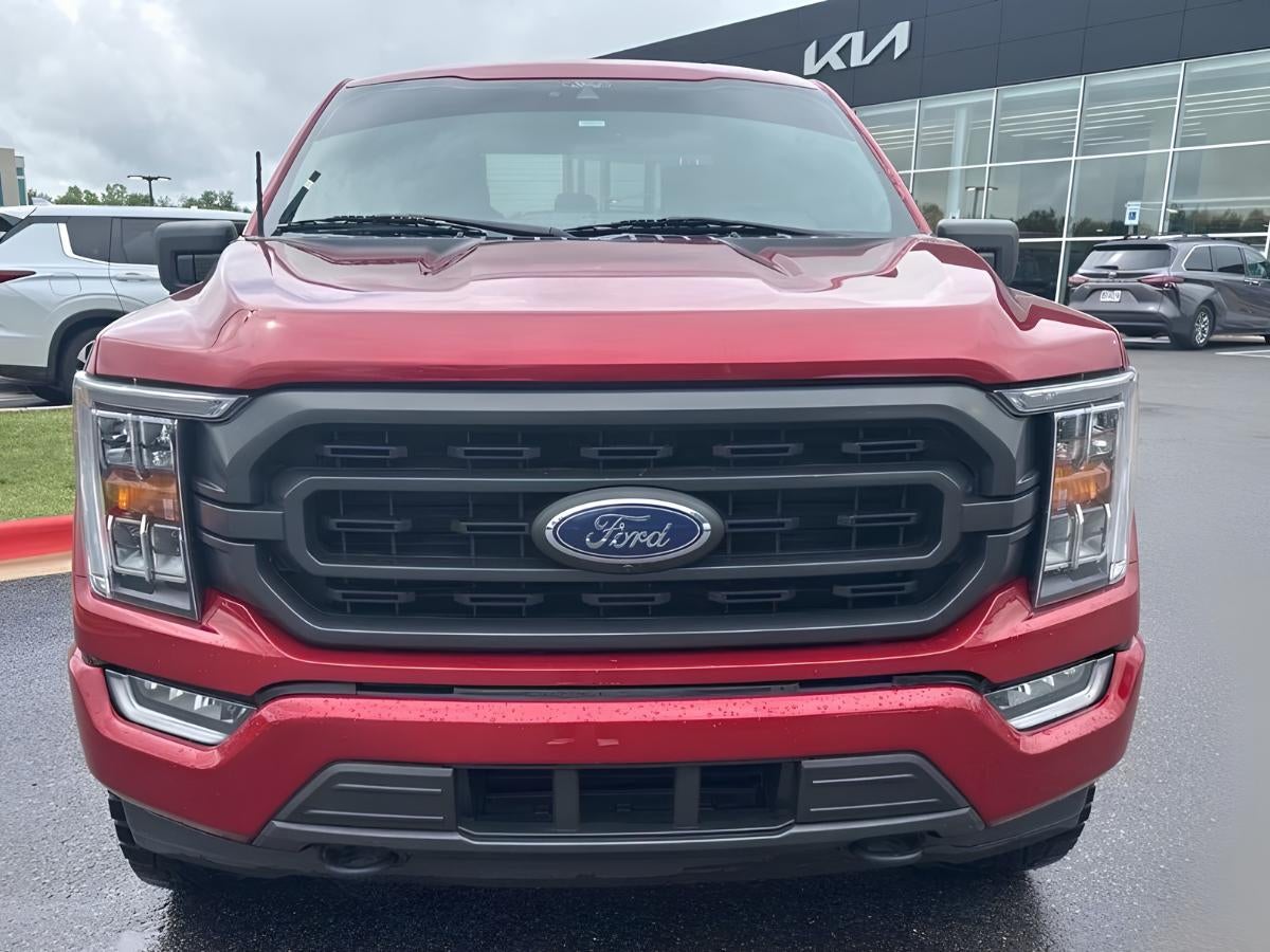 Red Ford F-150 parked in front of Crain Kia of Bentonville dealership