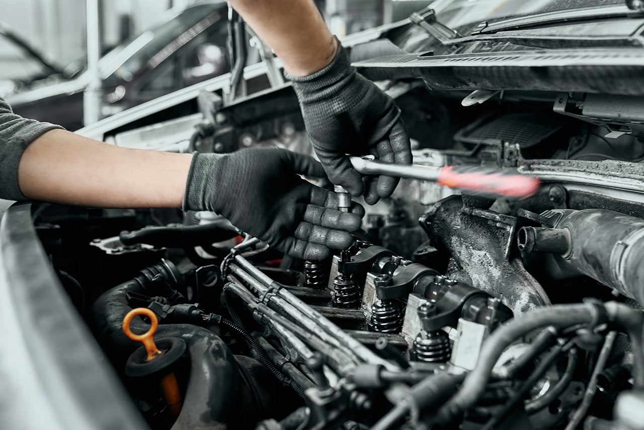 Qualified man in black dirty gloves unscrews old spark plugs