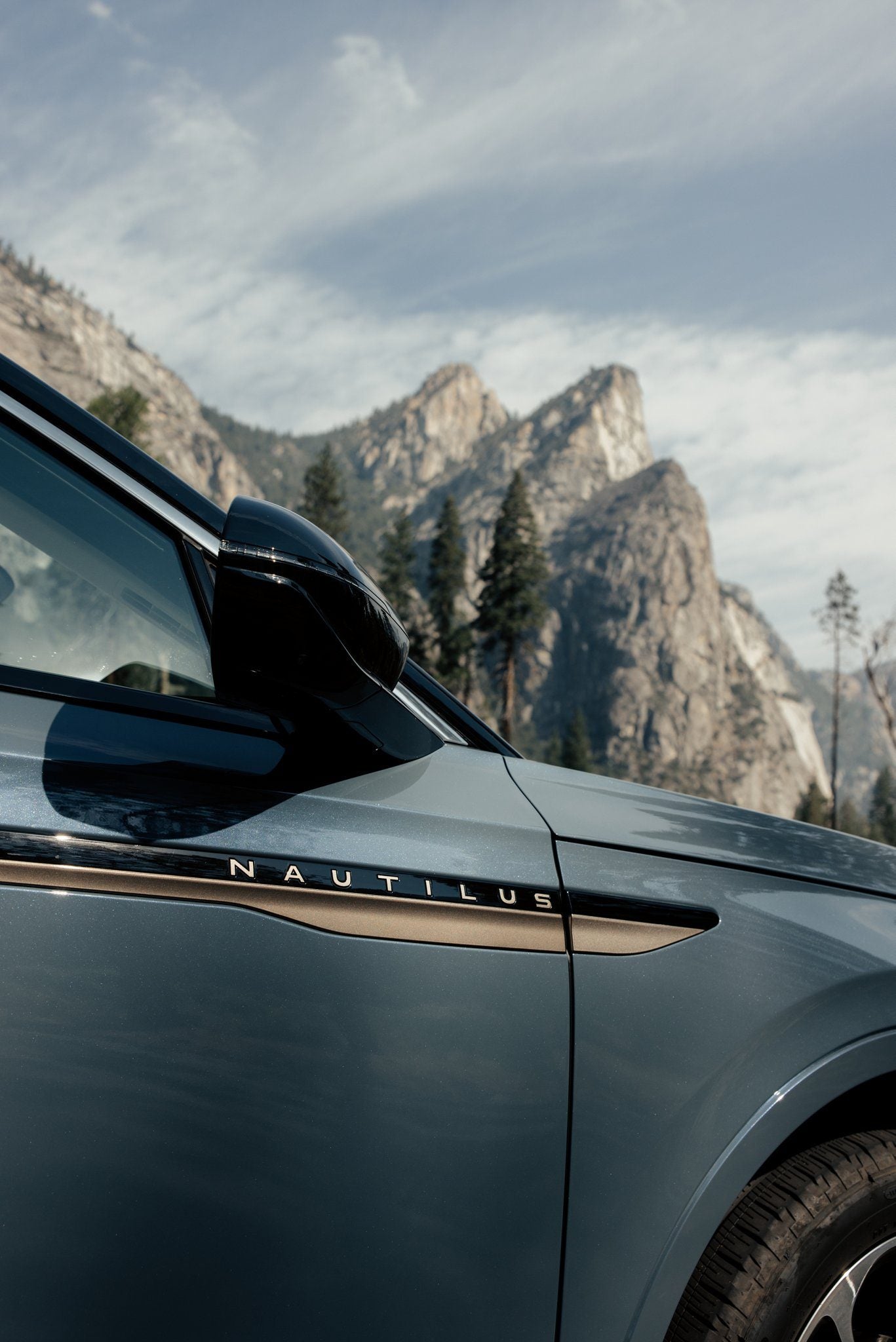Side fender of a gray blue Lincoln Nautilus with the Nautilus script, rocky mountains behind