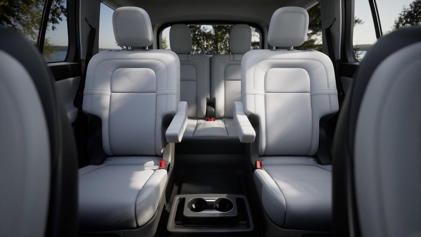 Second and third row gray leather seats inside a Lincoln Aviator seen from the rear
