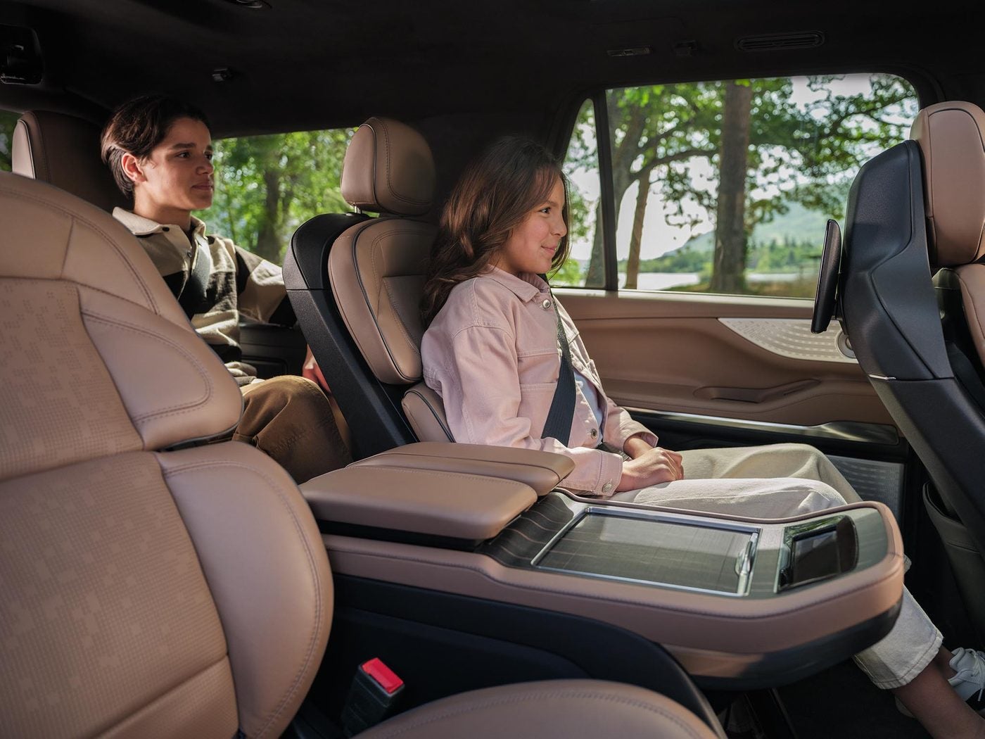 Two passengers seated in the brown leather second row captain chairs of a Lincoln Navigator