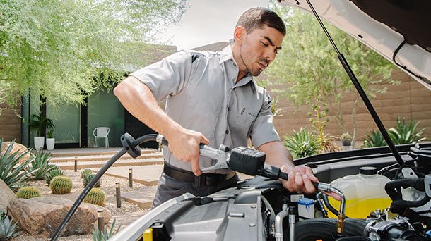 Lincoln technician in a gray uniform working under an open hood