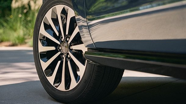 Close view of a Lincoln alloy wheel and tire on a paved road