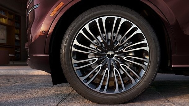 Maroon Lincoln SUV with a multi spoke wheel on pavement