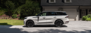 Sales advisor handing check to customer in front of Lincoln dealership.