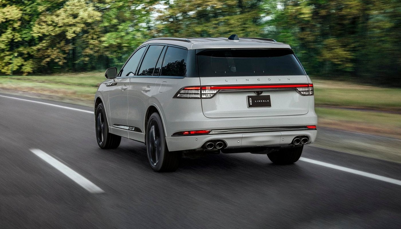 White Lincoln Aviator driving away on a highway with trees on both sides