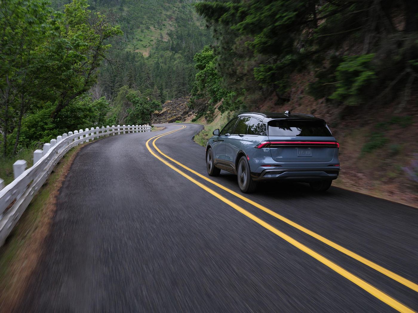 Lincoln Nautilus driving away on a curving two lane road through the hills